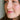 A young woman with brown eyes is looking off to the side with a slight smile on her lips. The focus is on her lips where you can see a lovely coral color. She is wearing bubblegum lip tint.