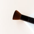 a black makeup brush with brown bristles that come to a flat, blunt shape on top. The bristles are medium to dense packed.