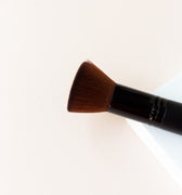 a black makeup brush with brown bristles that come to a flat, blunt shape on top. The bristles are medium to dense packed.