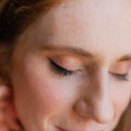 Young red head woman wearing soft black eyeliner in a wing. 