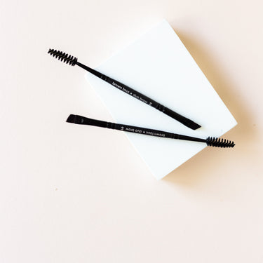 two brushes side by side. One side is a spool and the other side shows an angled brush similar to an eyeliner brush.