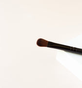 The top half of a black brush with dark brown bristles. The bristles seem to be in a flat line with a slight rounding on the top. The bristles are packed with a medium density and appears to look slightly fluffy. 