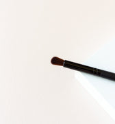 A small, semi-dense brush. The brush is black and the bristles are a dark brown.